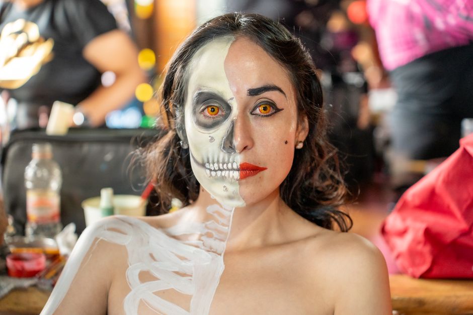 Half-face Catrina makeup art on a woman, showcasing Mexican tradition during Day of the Dead festival in CDMX.
