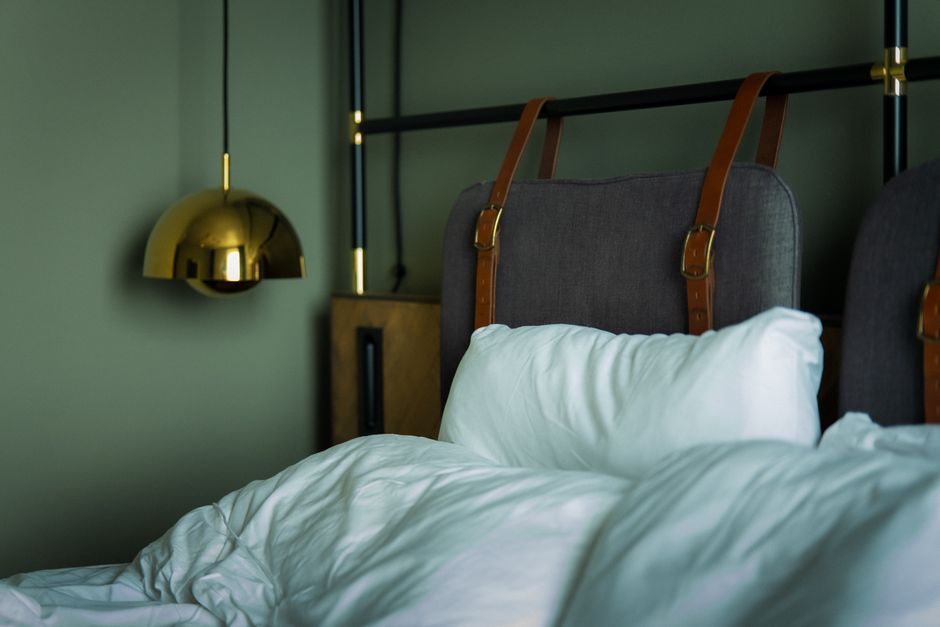 A cozy, modern bedroom interior with stylish lighting and luxurious bedding.