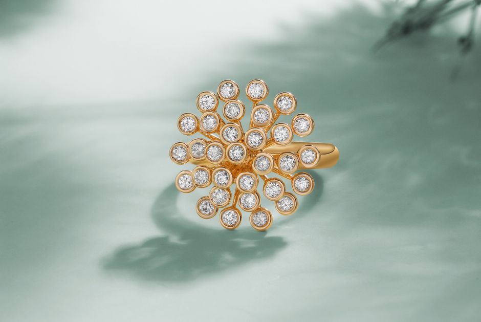Close-up of a luxury gold ring with diamonds against a teal background, showcasing elegance.