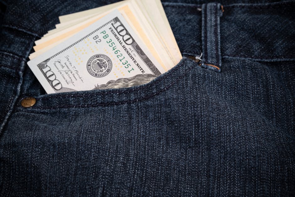 Close-up of hundred-dollar bills in a denim jeans pocket, symbolizing wealth and fashion.