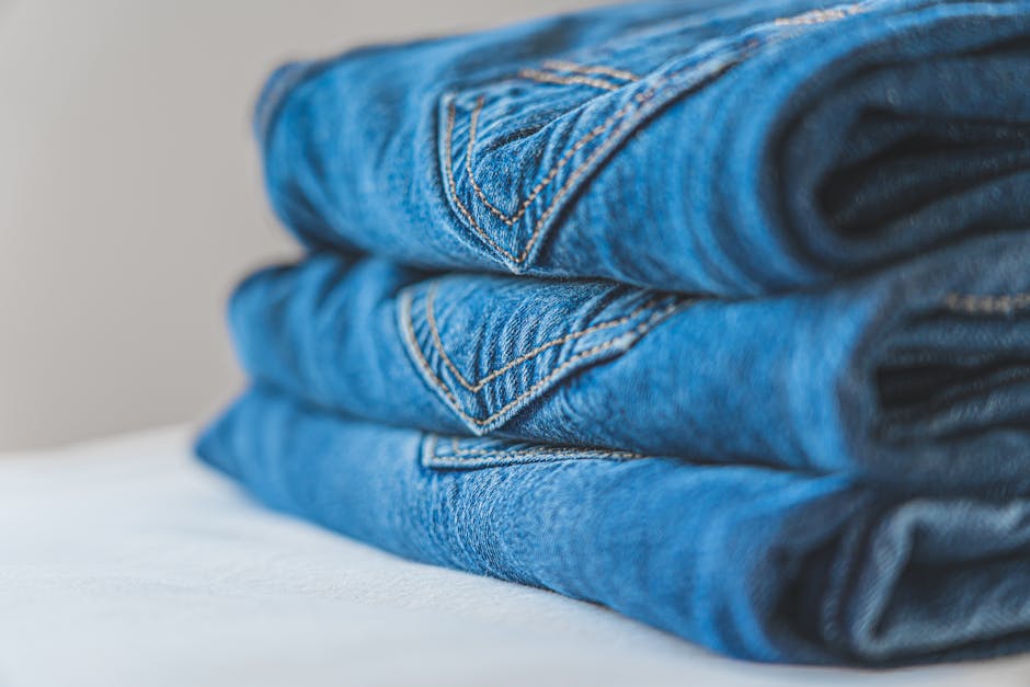 Close-up of neatly folded blue denim jeans on a white surface.