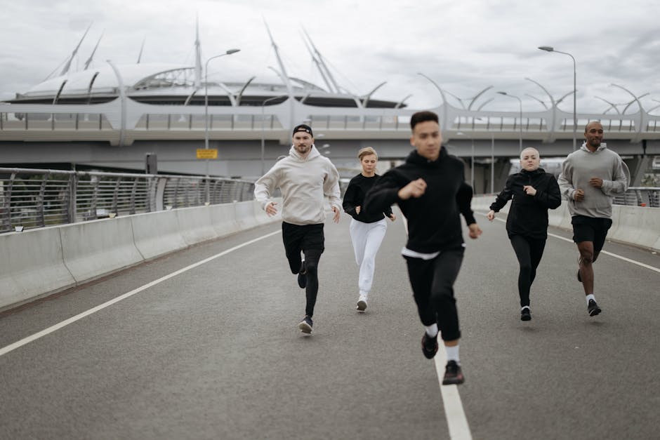 A group of diverse adults jogging on an urban road next to a modern stadium.