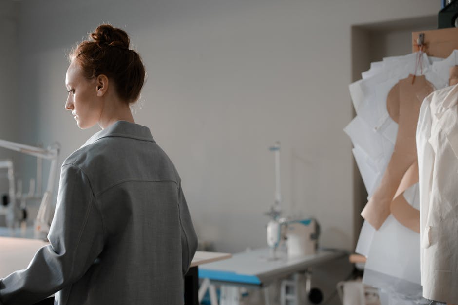 Woman in a fashion studio examining sewing patterns next to her sewing machine.