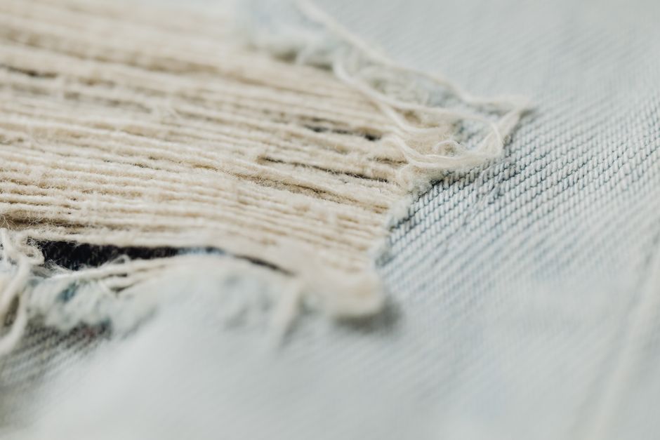 Detailed macro shot showcasing the frayed texture of a denim fabric, highlighting its woven pattern and wear.