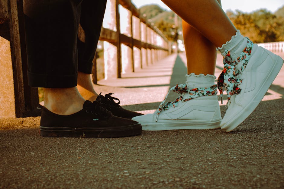 Close-up of a couple's stylish shoes on a sunlit bridge, showcasing casual fashion.